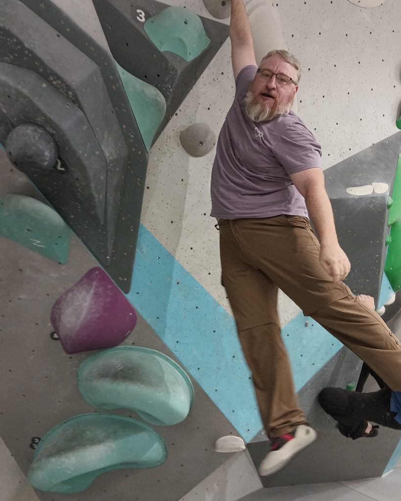 Kollege hängt beim Bouldern an einem Arm
